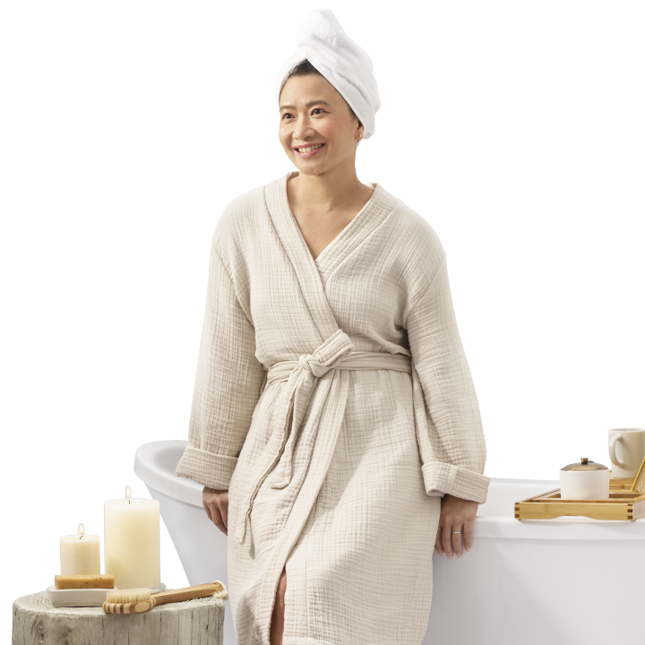 middle aged Asian woman leaning on her bathtub smiling in her renovated bathroom